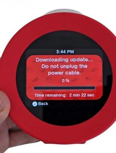 Un primo piano dell'Orologio sonoro Nintendo Alarmo con il display che mostra le istruzioni per il download di un nuovo aggiornamento di sistema.