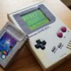 Game Boy originale DMG-01 grigio con cassetta di Tetris appoggiata sopra