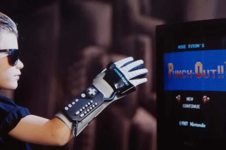 Un bambino gioca a Punch Out con il controller Power Glove per Nintendo NES mostrato con i suoi tasti programmabili e il design futuristico.