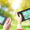 Due giocatori che usano il multiplayer locale e la funzione GameShare all'aperto su due console Nintendo Switch 2 separate.