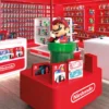 Area Nintendo Store all'interno del Gamelife CityLife di Milano, allestita con prodotti Nintendo Switch 2, amiibo e la statua iconica di Mario nel tubo verde